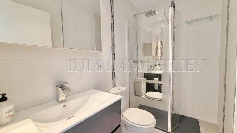 Modernes Badezimmer mit Waschtisch, WC und Glasdusche im Penthouse Cala Pi