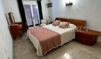 Helles Schlafzimmer der Meereslinie-Wohnung in El Arenal mit Doppelbett, Holzmöbeln und Balkonzugang.