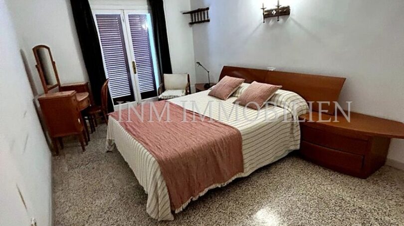 Helles Schlafzimmer der Meereslinie-Wohnung in El Arenal mit Doppelbett, Holzmöbeln und Balkonzugang.