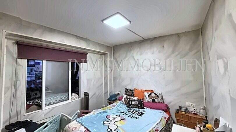 Kleines Schlafzimmer mit Doppelbett, grauer Tapete, Deckenleuchte und Fenster zur Loggia in Strandnähe, Palma
