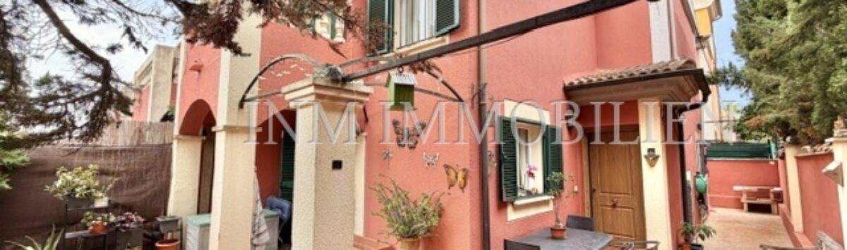 Außenansicht: Gepflegtes rotes Reiheneckhaus mit überdachter Terrasse, Gartenmöbeln und Bepflanzung in Pollença.