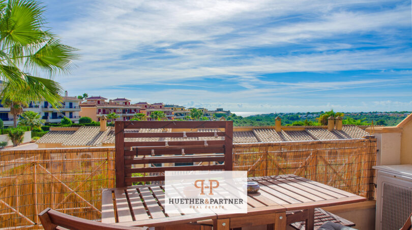 Dachterrasse der Wohnung in Cales de Mallorca mit Holzmöbeln, Bambuszaun und Meerblick