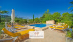 Zona de piscina de la finca Felanitx con tumbonas amarillas, sombrilla y vistas a montañas boscosas