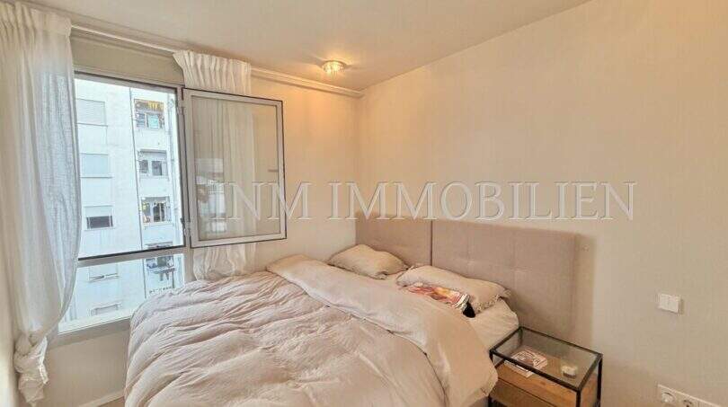 Helles Schlafzimmer der Maisonette in Son Armadans mit Doppelbett, Polsterkopfteil und Stadtblick durchs Fenster.