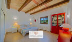 Dormitorio luminoso de la finca Felanitx con techo de vigas de madera, armario rojo y cama doble