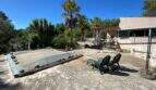 Mediterraner Außenbereich der Finca in Algaida mit abgedecktem Pool, Steinboden, Liegestühlen und Palmen.