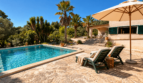 Poolbereich der mediterranen Finca in Algaida mit Liegestühlen, Sonnenschirm und Palmen unter blauem Himmel.