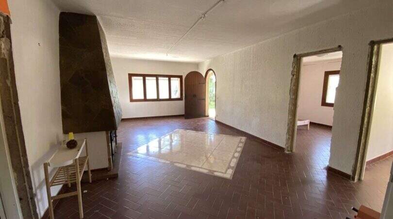 Amplia sala de estar de la finca en Algaida con suelo de terracota, chimenea y puerta de entrada de arco.