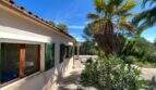 Außenansicht der mediterranen Finca in Algaida mit grünen Fensterläden, Palme und gepflegtem Garten.