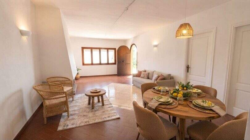Luminosa sala-comedor de la finca mediterránea en Algaida con muebles de ratán, mesa de madera y suelo rústico de terracota.