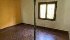 Renovierungsbedürftiger Raum der Finca mit Terrakottaboden, Stützstrebe und freiliegenden Deckenbalken.