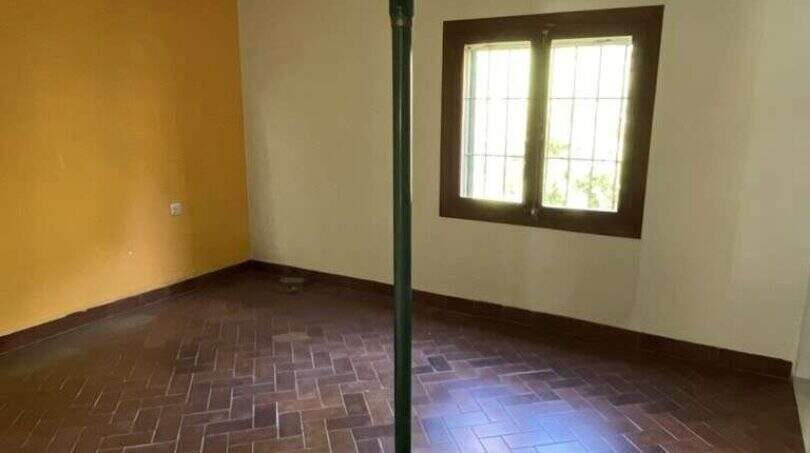 Renovierungsbedürftiger Raum der Finca mit Terrakottaboden, Stützstrebe und freiliegenden Deckenbalken.