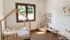 Habitación infantil de la finca con cama tipo casa, lámpara de globo aerostático y suelo de terracota en Algaida