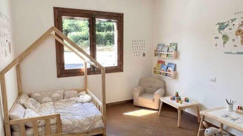 Habitación infantil de la finca con cama tipo casa, lámpara de globo aerostático y suelo de terracota en Algaida