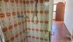 Ducha con azulejos retro estampados en naranja y suelo de terracota en finca mediterránea Algaida