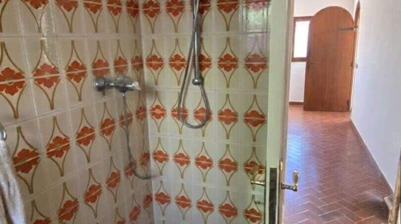 Ducha con azulejos retro estampados en naranja y suelo de terracota en finca mediterránea Algaida