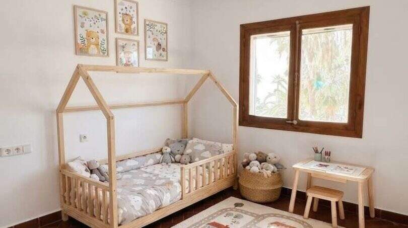 Habitación infantil de la finca en Algaida con cama tipo casa, alfombra de juegos y lámpara de pantalla de globo aerostático encantadora.