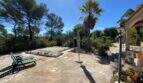 Mediterraner Außenbereich der Finca in Algaida mit abgedecktem Pool, Natursteintetrasse, Palmen und Liegestühlen.