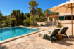 Piscina soleada con tumbonas y sombrilla, finca mediterránea rodeada de palmeras en Algaida