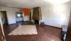 Amplia sala de estar de la finca en Algaida con chimenea de piedra, suelo de terracota y acento de pared naranja.