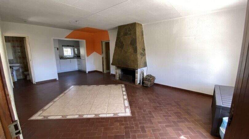 Amplia sala de estar de la finca en Algaida con chimenea de piedra, suelo de terracota y acento de pared naranja.
