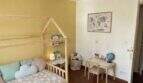Habitación infantil de la finca en Algaida con cama tipo casa, lámpara de globo aerostático y suelo mediterráneo de terracota.