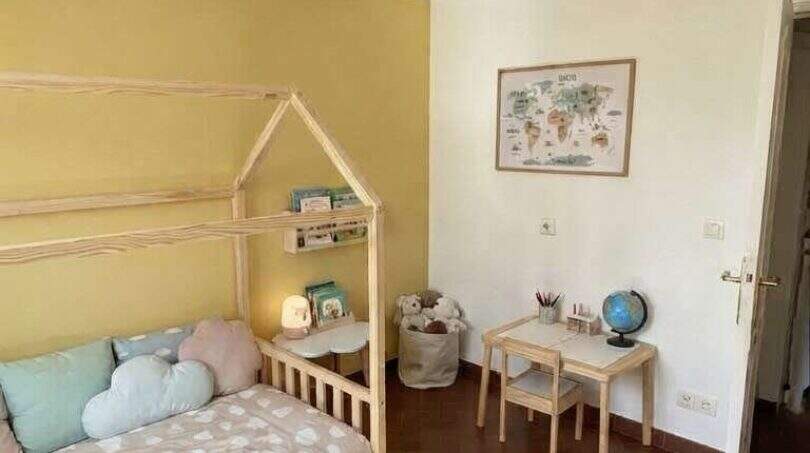 Habitación infantil de la finca en Algaida con cama tipo casa, lámpara de globo aerostático y suelo mediterráneo de terracota.