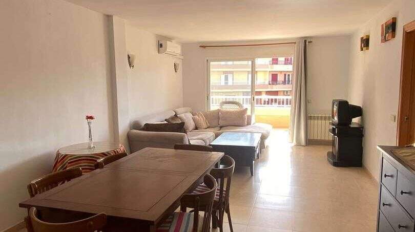 Helles Wohn-Esszimmer der Ruheoase in Porto Cristo mit Holztisch, Sofa und Balkonzugang.