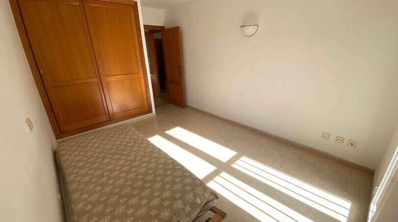 Helles Schlafzimmer der Ruheoase in Porto Cristo mit Einbauschrank aus Holz und Fliesenboden.