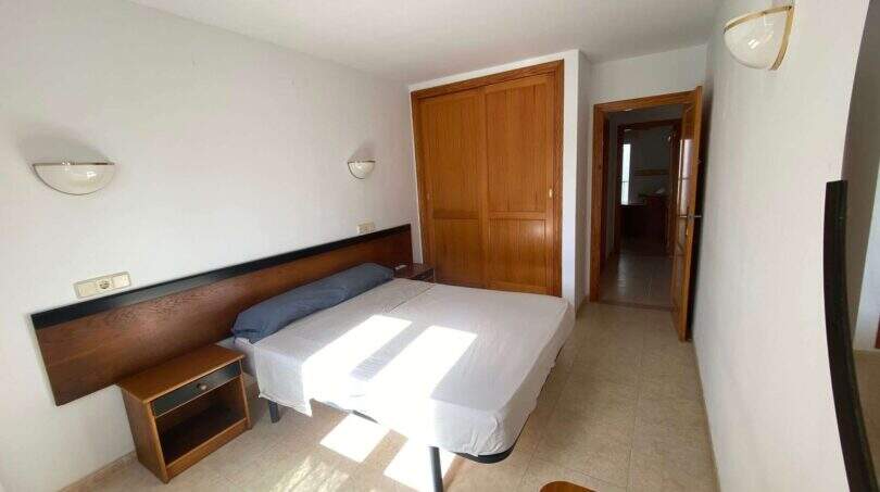 Helles Schlafzimmer der Ruheoase in Porto Cristo mit Doppelbett, Holzschrank und modernen Wandleuchten.