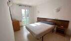 Helles Schlafzimmer der Ruheoase in Porto Cristo mit Doppelbett, Holzkopfteil, Klimaanlage und Balkonzugang.