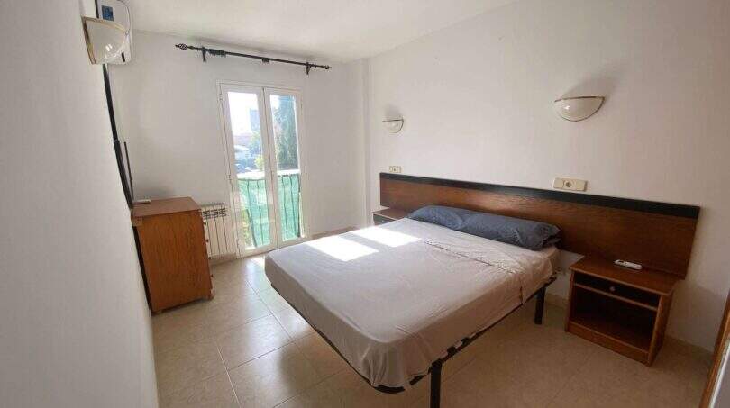 Helles Schlafzimmer der Ruheoase in Porto Cristo mit Doppelbett, Holzkopfteil, Klimaanlage und Balkonzugang.