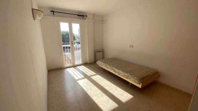 Helles Schlafzimmer der Ruheoase in Porto Cristo mit Einzelbett, Fliesenboden, Balkonzugang und Klimaanlage.