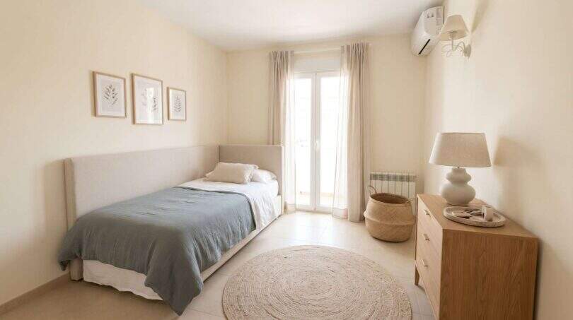 Helles Schlafzimmer der Ruheoase in Porto Cristo mit Einzelbett, Holzkommode, Klimaanlage und Balkonzugang.