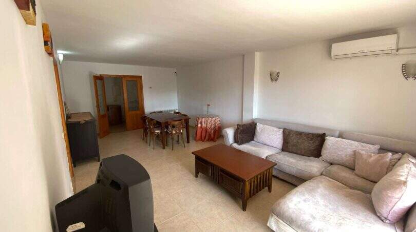 Helles Wohnzimmer der Ruheoase in Porto Cristo mit Ecksofa, Couchtisch, Essbereich und Klimaanlage.