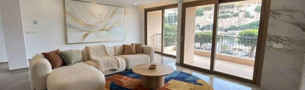 Helles Wohnzimmer mit Bouclésofa, buntem Teppich und Panorama-Schiebetüren mit Hafenblick in Porto Cristo.