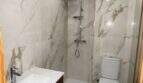 Modernes Badezimmer mit Marmoroptik-Fliesen, Walk-in-Dusche, WC und Holz-Waschtisch in Porto Cristo.