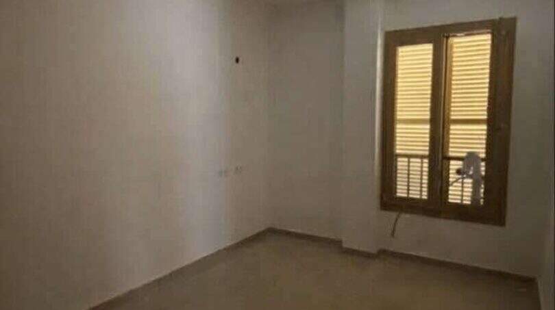 Leeres Zimmer mit Holzfenster und glänzendem Fliesenboden in Hafenwohnung Porto Cristo