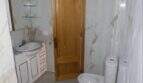 Modernes Badezimmer mit Marmorfliesen, Waschtisch, WC und Holztür in exklusiver Hafenwohnung Porto Cristo