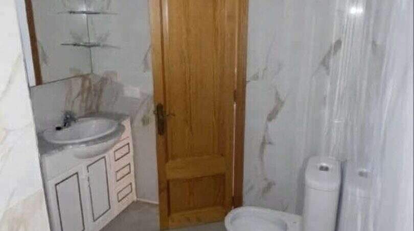 Modernes Badezimmer mit Marmorfliesen, Waschtisch, WC und Holztür in exklusiver Hafenwohnung Porto Cristo