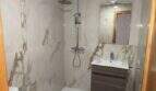 Modernes Badezimmer mit Marmoroptik-Fliesen, bodenebener Dusche, schwebendem Waschtisch und WC in Hafenwohnung Porto Cristo