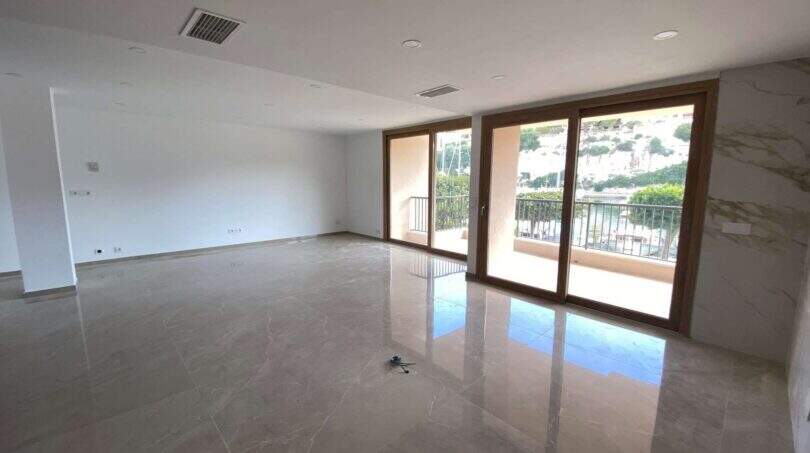 Helles, leeres Wohnzimmer mit Marmorböden und Balkon mit Meerblick in exklusiver Hafenwohnung Porto Cristo