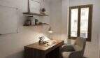 Modernes Arbeitszimmer mit Holzschreibtisch, Laptop, Wandregalen und Fenster in Hafenwohnung Porto Cristo