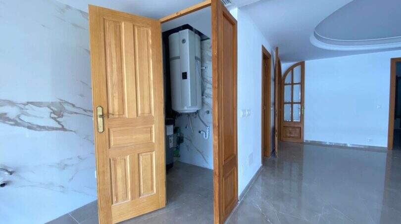 Flur der Hafenwohnung Porto Cristo mit Holztüren, Marmorboden und sichtbarem Technikraum mit Warmwasserspeicher