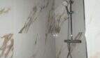 Modernes Duschsystem in Chromoptik mit Regendusche vor eleganten Marmorfliesen in der Hafenwohnung Porto Cristo
