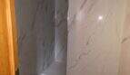 Modernes Badezimmer mit eleganten Marmorfliesen und dunklem Steinboden in der Hafenwohnung Porto Cristo