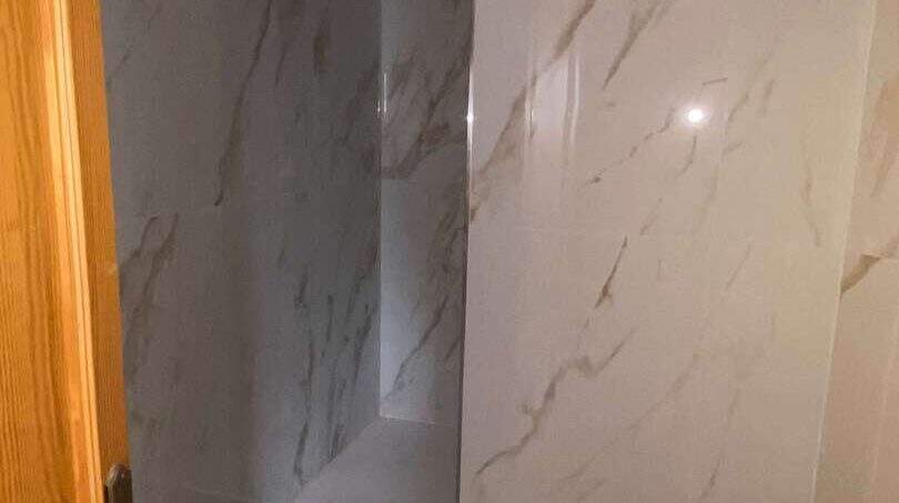 Modernes Badezimmer mit eleganten Marmorfliesen und dunklem Steinboden in der Hafenwohnung Porto Cristo