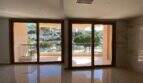 Heller Wohnraum mit Marmorböden und zwei Glasschiebetüren zum Balkon mit Hafenblick in Porto Cristo