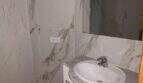 Elegantes Badezimmer mit Marmorwänden, weißem Waschtischunterschrank und großem Spiegel in Hafenwohnung Porto Cristo