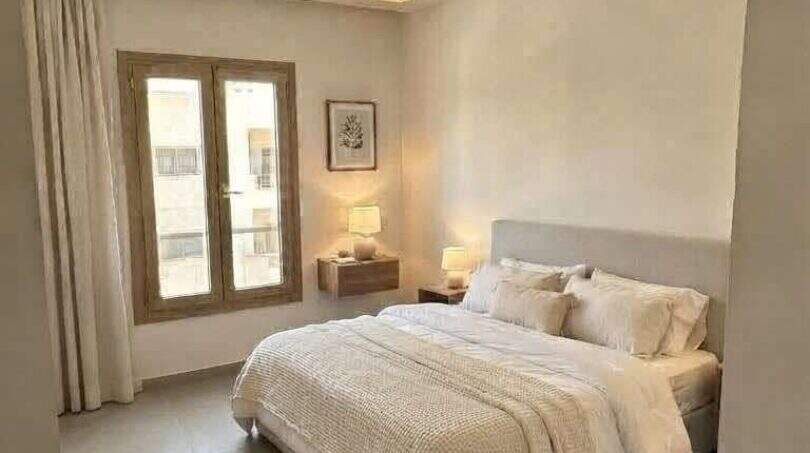 Helles Schlafzimmer mit Doppelbett, indirekter Deckenbeleuchtung und Natursteinboden in exklusiver Hafenwohnung Porto Cristo
